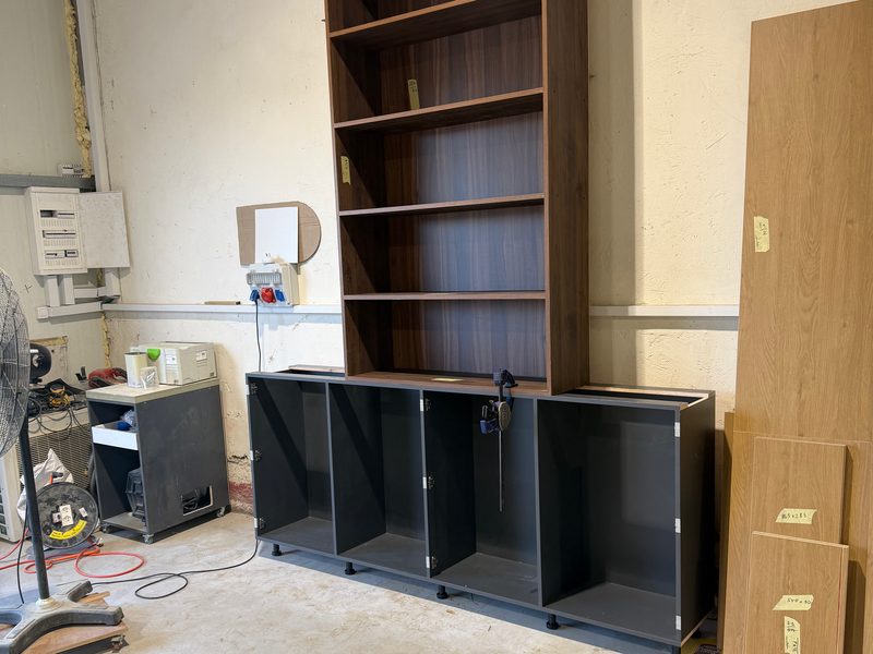 Dark wood-grain bookcase on dark base cabinets, assembled in the workshop