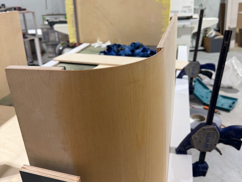 Curved panel clamped to form a rounded cabinet side