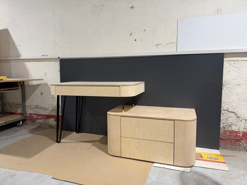 Desk with hairpin legs beside a rounded drawer unit, unfinished