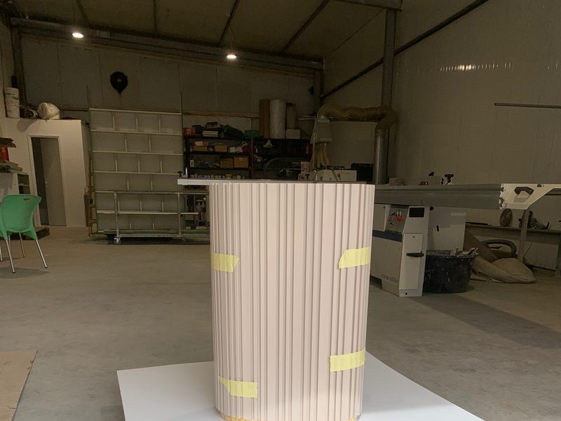 Fluted column cladding on the workshop floor, masking tape at the base