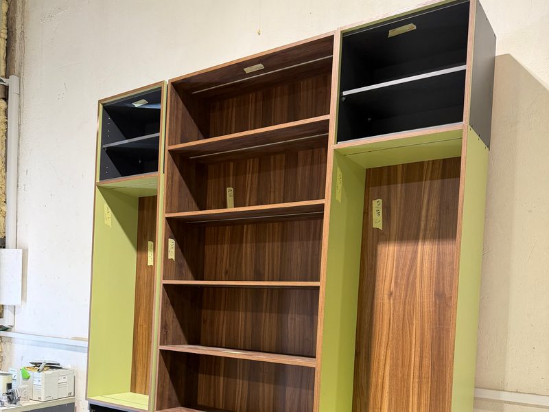Bookcase unit with green side panels and dark base cabinets, in the workshop