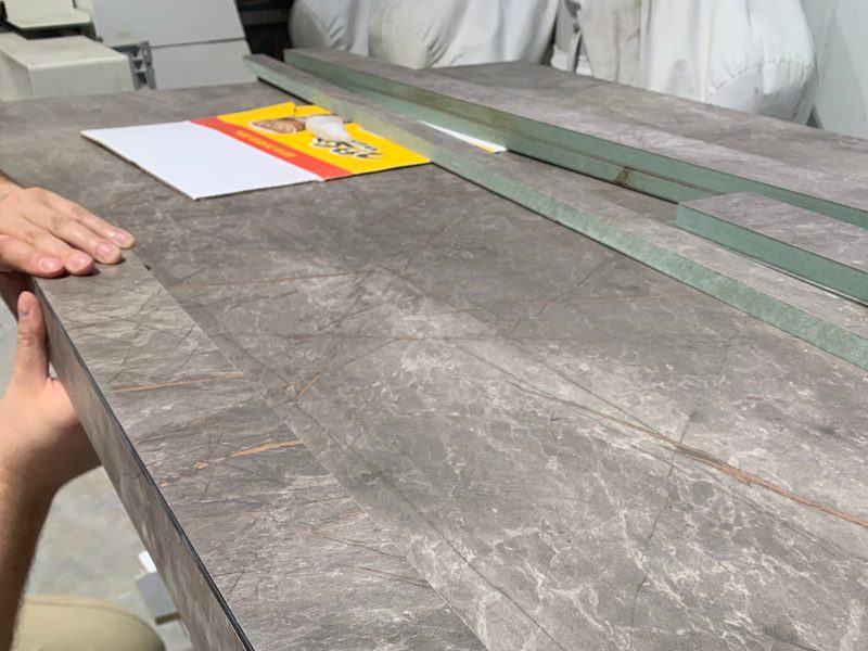 A hand checking a grey worktop panel in the workshop