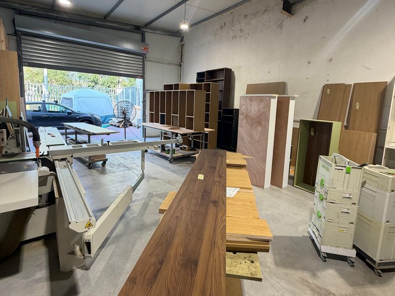 A long dark wood-grain board on the bench, the roller door open behind