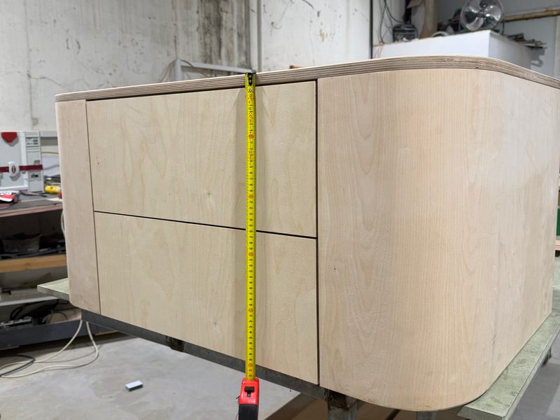 Rounded cabinet on the bench with a tape measure checking its height
