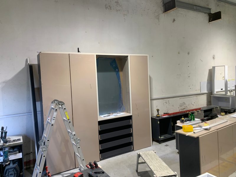 Wardrobe with drawers and a panel under protective film, base cabinets beside it