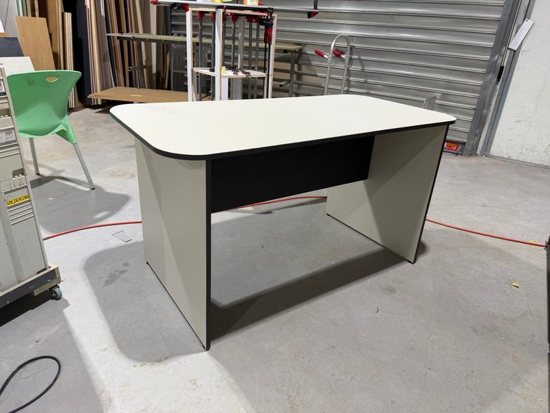 Desk with a white top and black edge, in the workshop