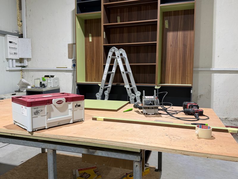 Workbench with a tool case and power tools in front of the bookcase unit