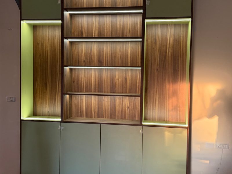 Large bookcase with lit shelves, green side niches and green doors below