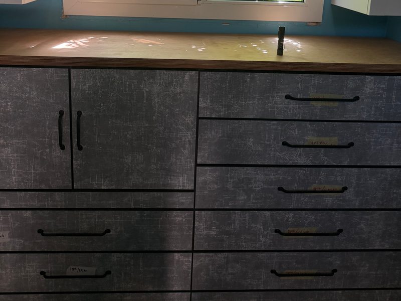 Grey textured chest of drawers and cupboards under a window
