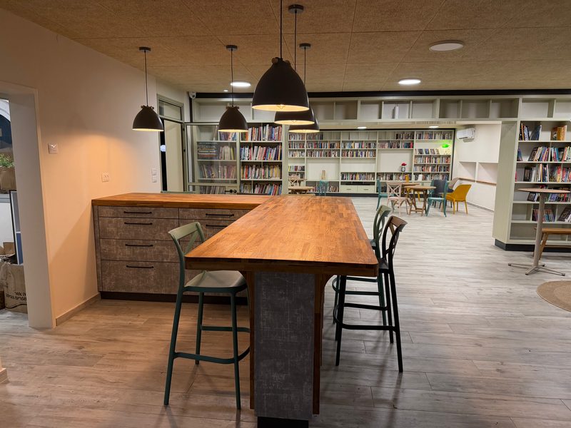 Counter with bar stools under pendant lights, bookshelves behind
