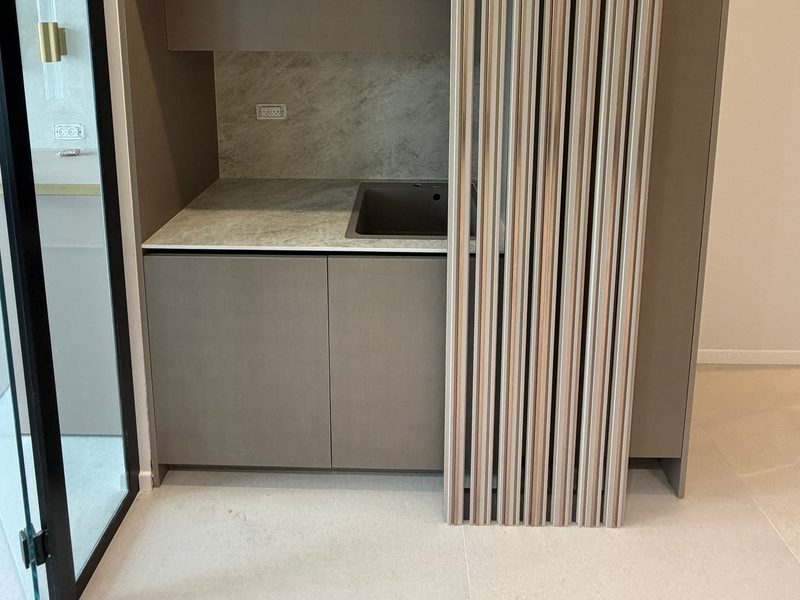 Kitchenette built into tall cabinets, with a grooved panel beside it